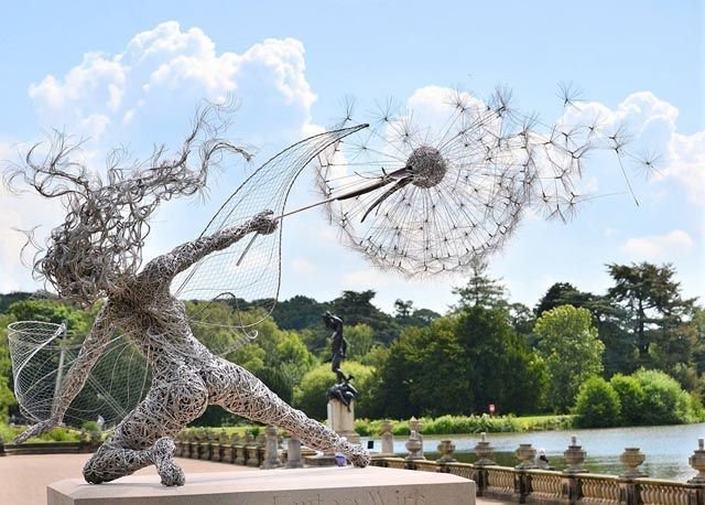 Black metal garden ornament with a winged fairy on a dandelion-style flower