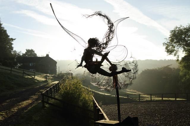 Black metal garden ornament with a winged fairy on a dandelion-style flower