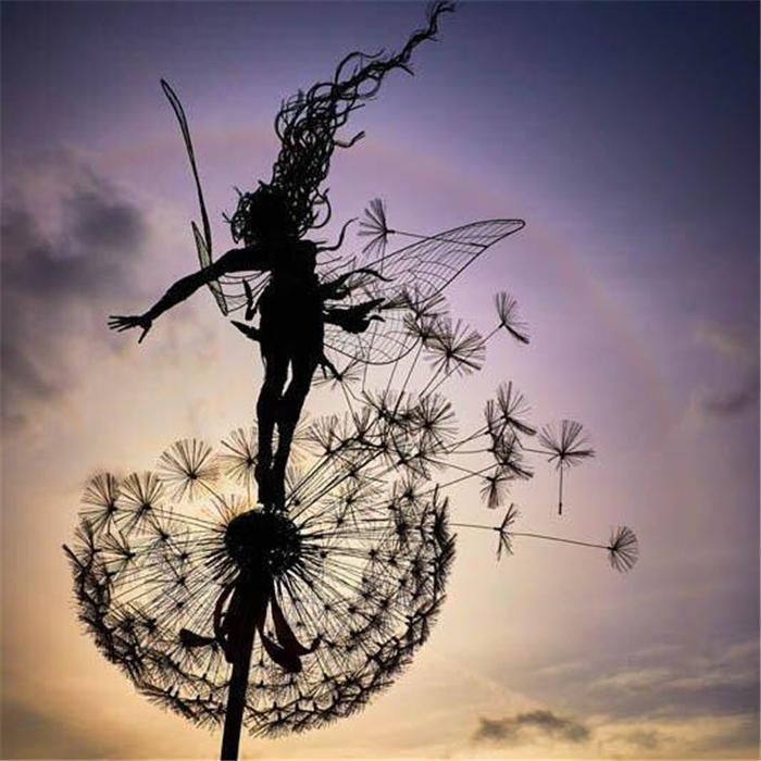 Black metal garden ornament with a winged fairy on a dandelion-style flower