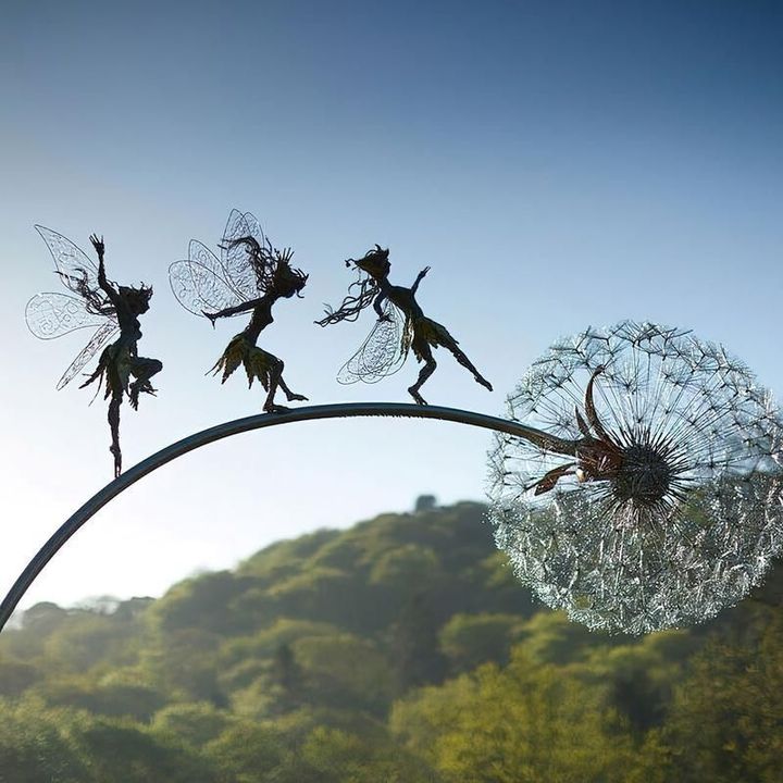 Black metal garden ornament with a winged fairy on a dandelion-style flower