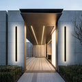 Slim linear outdoor wall lamp installed beside an entrance