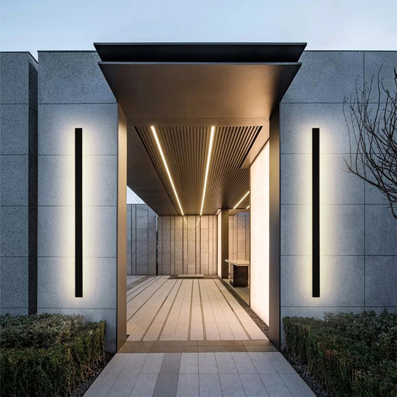 Slim linear outdoor wall lamp installed beside an entrance