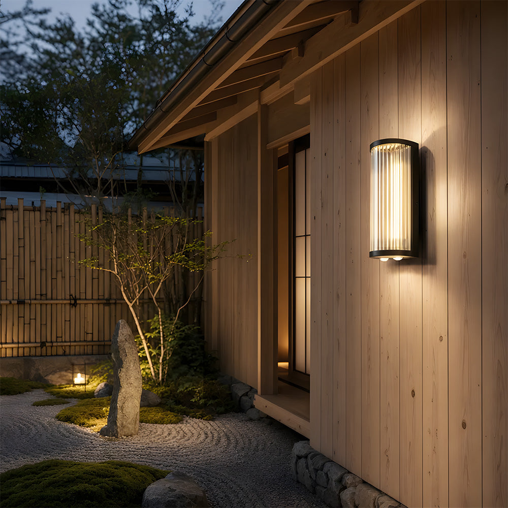 Black outdoor wall light with vertical glass shade and up and down illumination