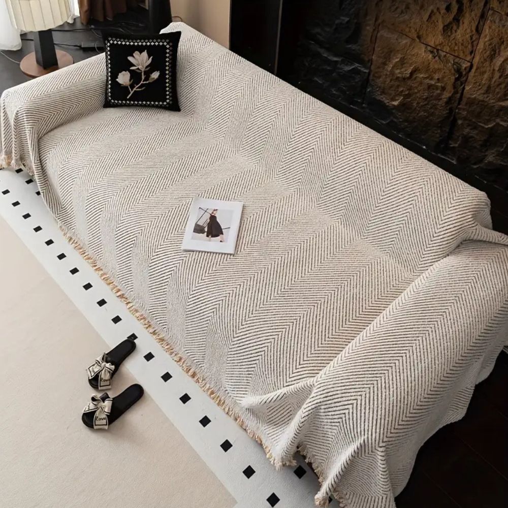 Herringbone sofa cover with textured pattern and fringed edge