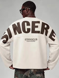 Beige oversized long sleeve top with bold dark text print on the back and sleeves