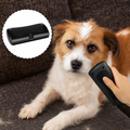 Black handheld dog grooming brush used on a dog's coat