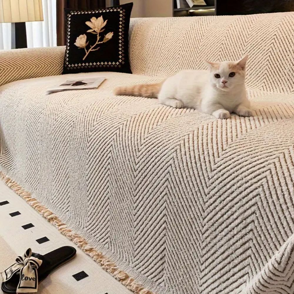 Herringbone sofa cover with textured pattern and fringed edge