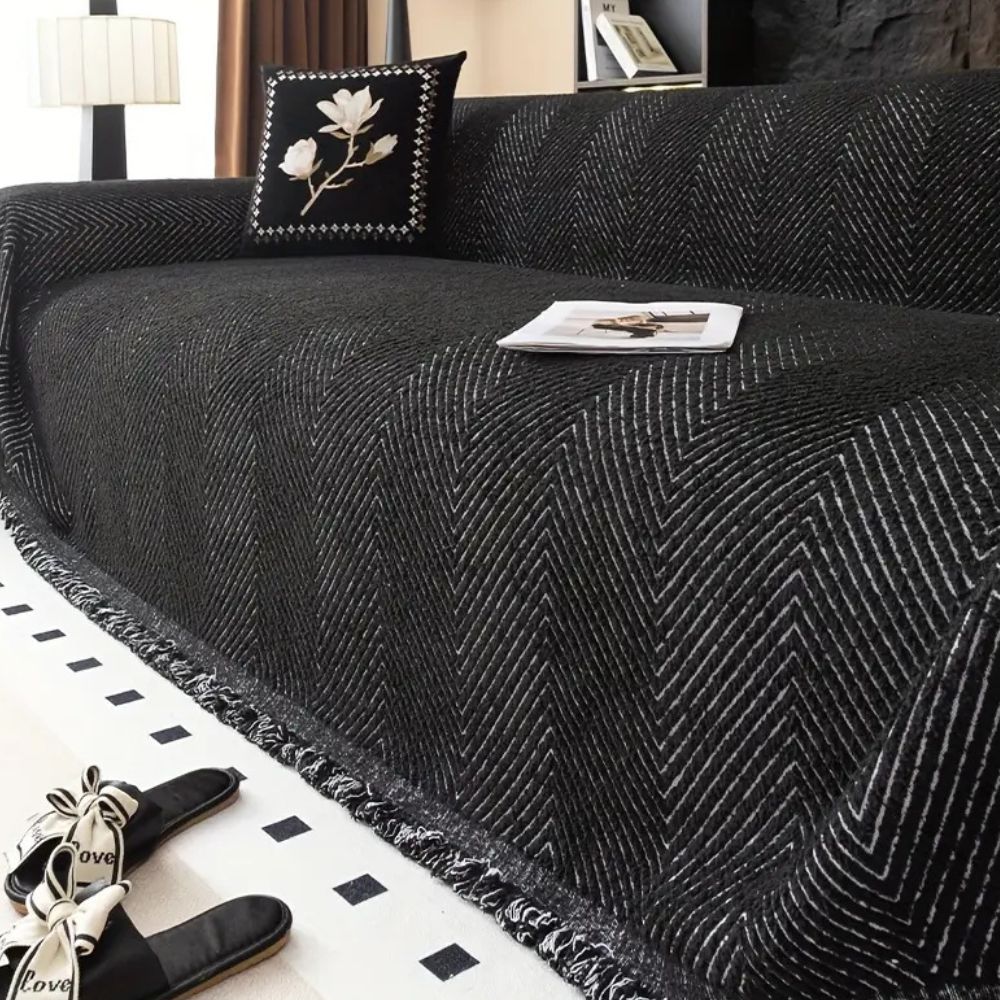 Herringbone sofa cover with textured pattern and fringed edge