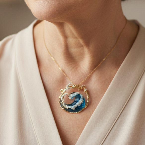 Gold-tone pendant necklace with blue ocean wave design and clear decorative stones