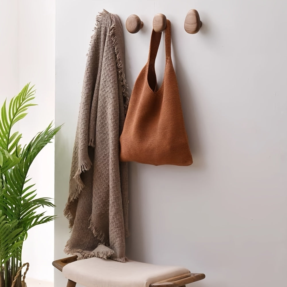 Pebble-shaped wooden decorative wall hooks mounted on a white wall