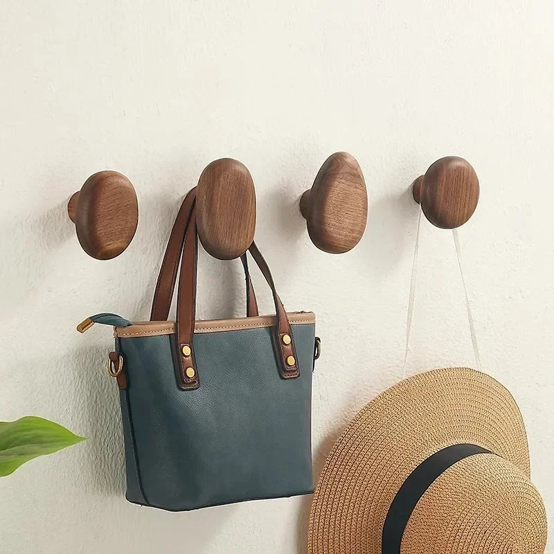 Pebble-shaped wooden decorative wall hooks mounted on a white wall