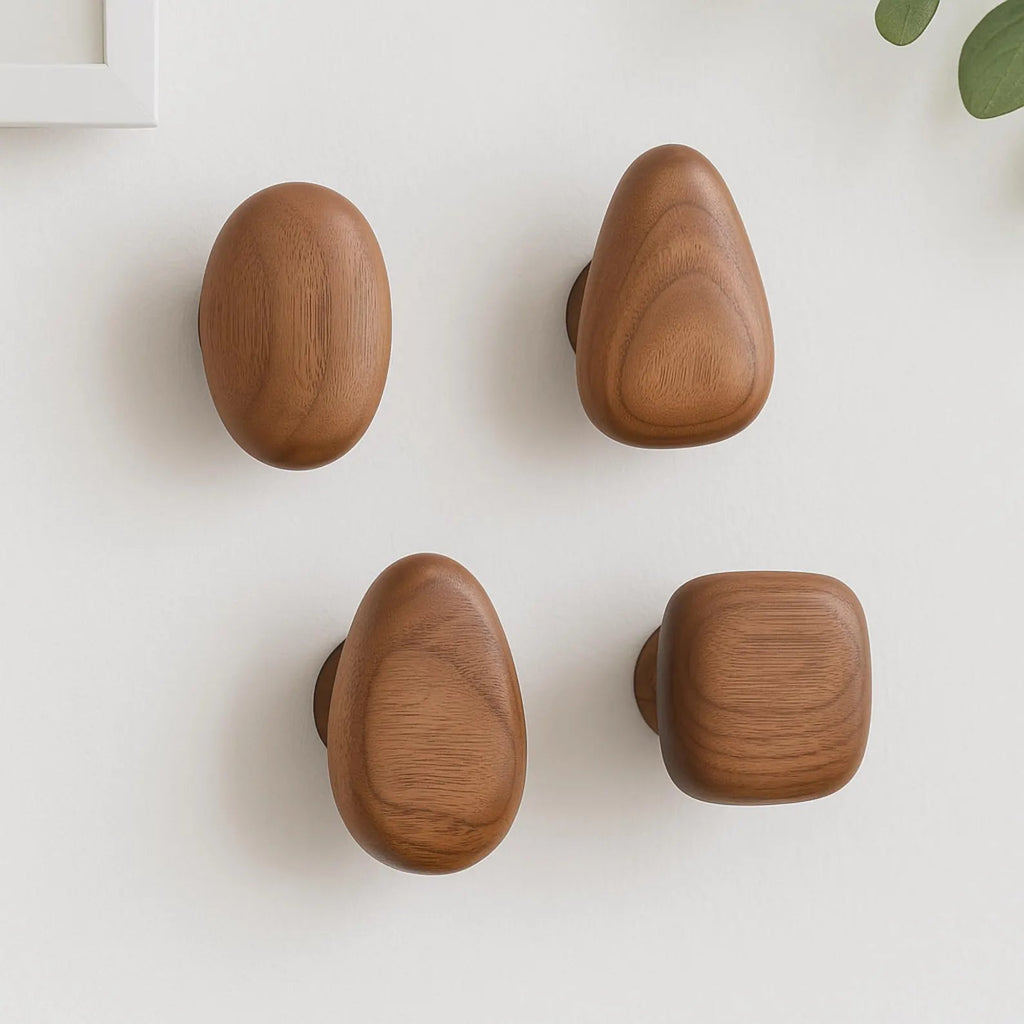 Pebble-shaped wooden decorative wall hooks mounted on a white wall