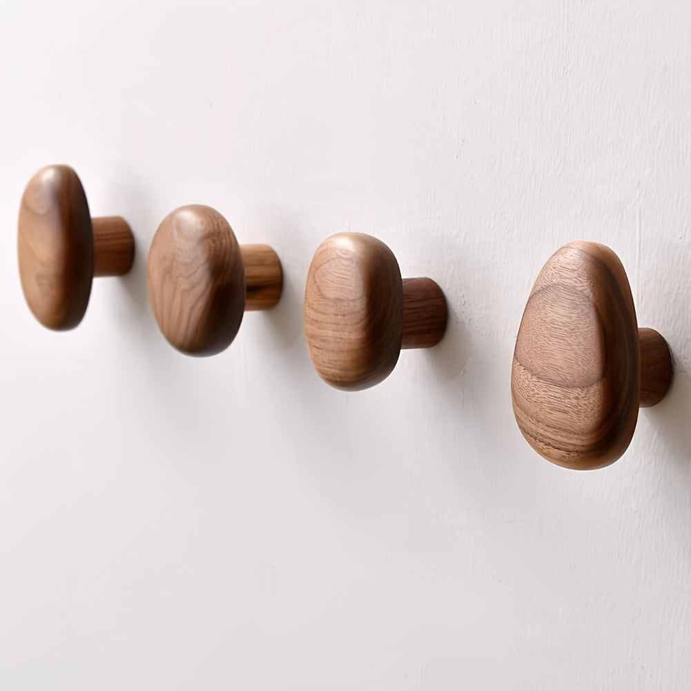 Pebble-shaped wooden decorative wall hooks mounted on a white wall