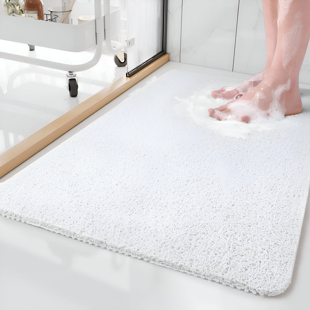 Textured rectangular bath mat with rounded corners on a bathroom floor