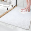 Textured rectangular bath mat with rounded corners on a bathroom floor