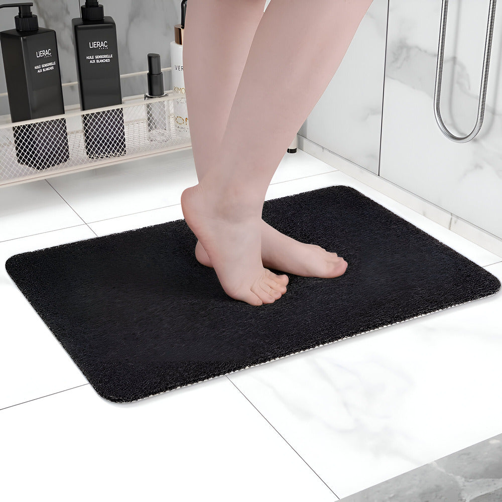 Textured rectangular bath mat with rounded corners on a bathroom floor