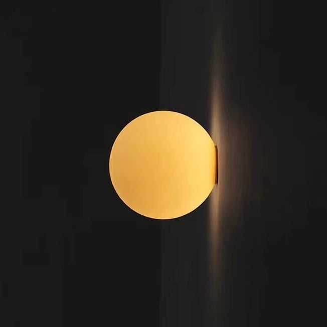 White frosted glass globe LED wall sconce mounted on a wall