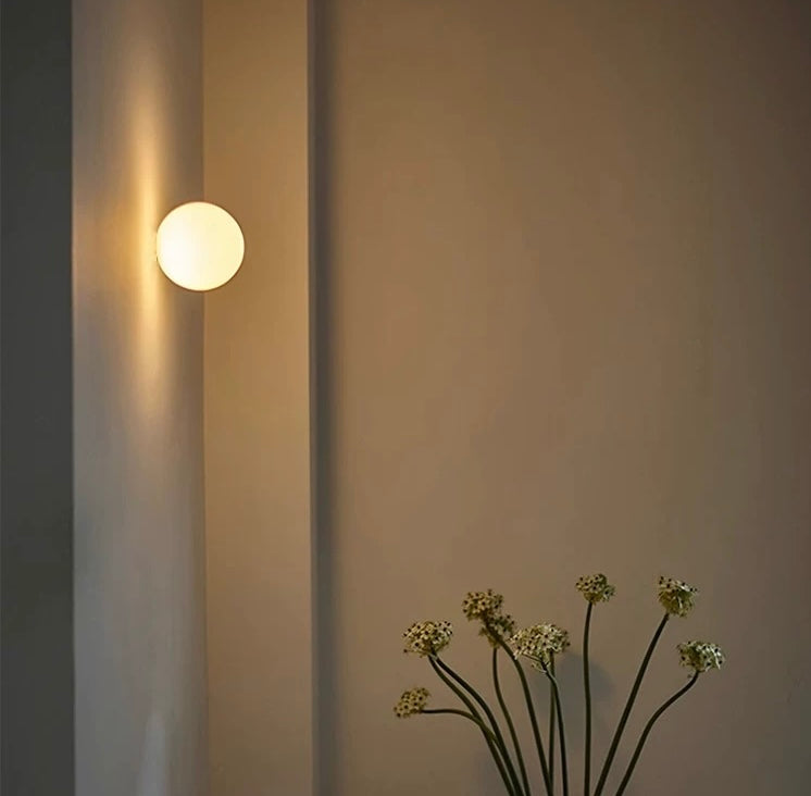 White frosted glass globe LED wall sconce mounted on a wall