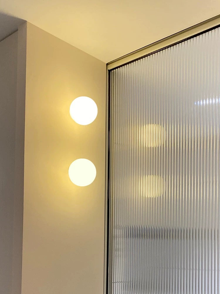 White frosted glass globe LED wall sconce mounted on a wall