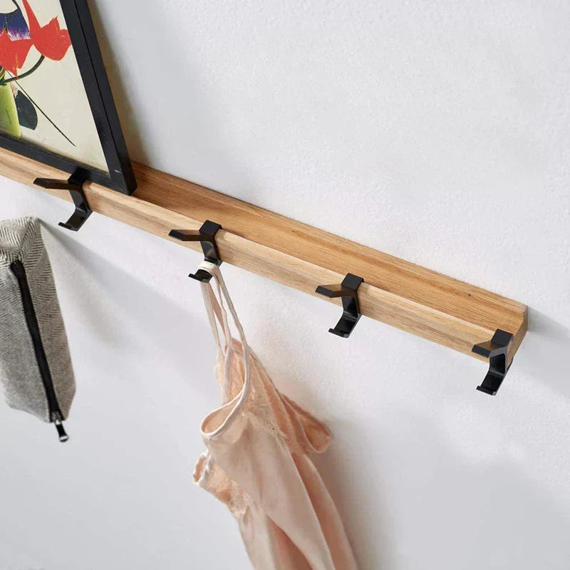 Wall-mounted coat rack with black hooks and a wood-effect bar