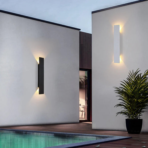 Black vertical outdoor LED wall light casting warm white light upward and downward