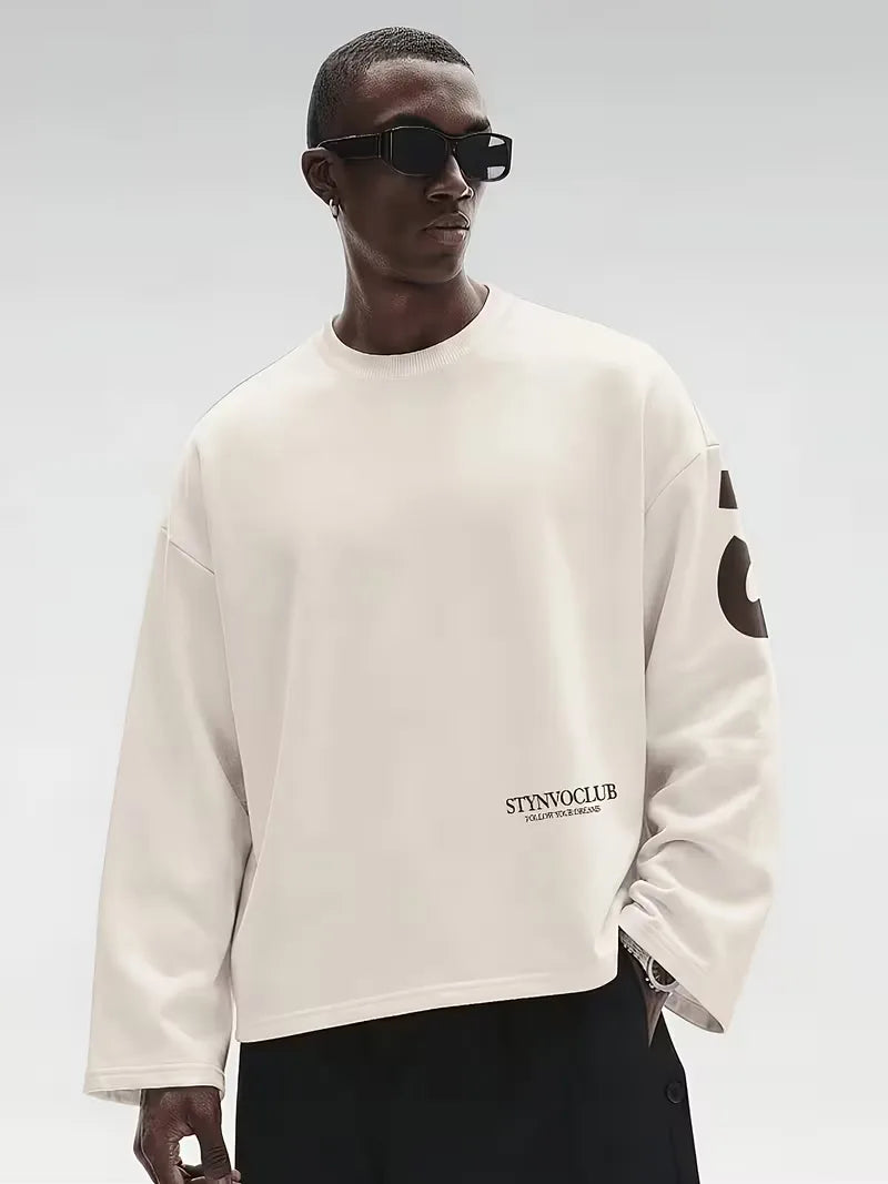 Beige oversized long sleeve top with bold dark text print on the back and sleeves