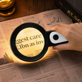 Black handheld magnifying glass with large round lens and white grip panel