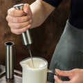 Silver cordless handheld milk frother with whisk head and storage sleeve