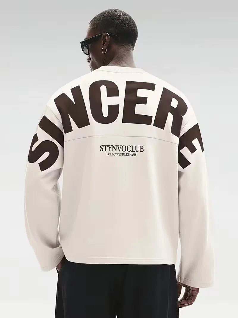 Beige oversized long sleeve top with bold dark text print on the back and sleeves