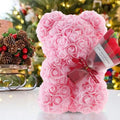 Teddy bear decoration covered in rose-shaped flowers with a bouquet and ribbon
