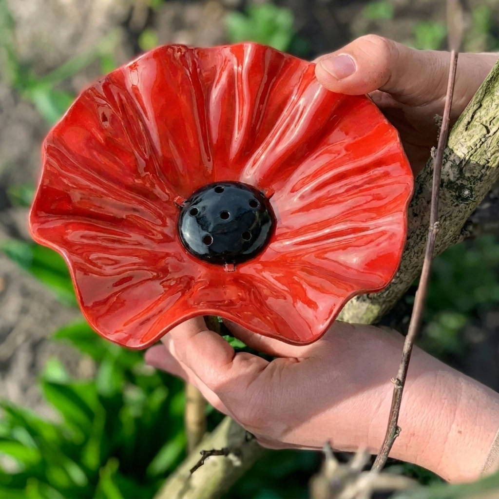 Red flower-shaped bird bath bowl on a black garden stake