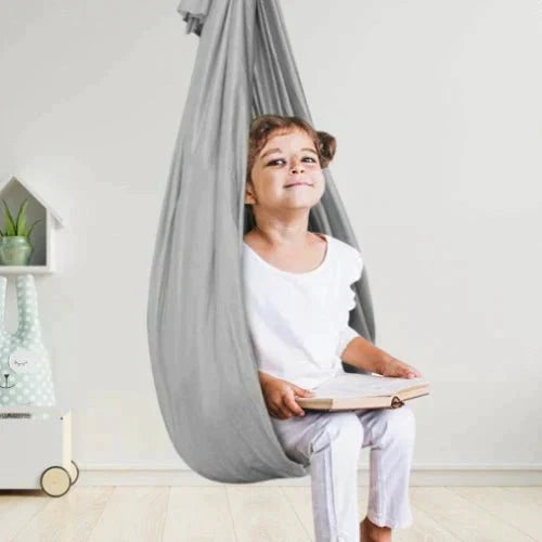Child sitting in a fabric indoor hanging pod swing